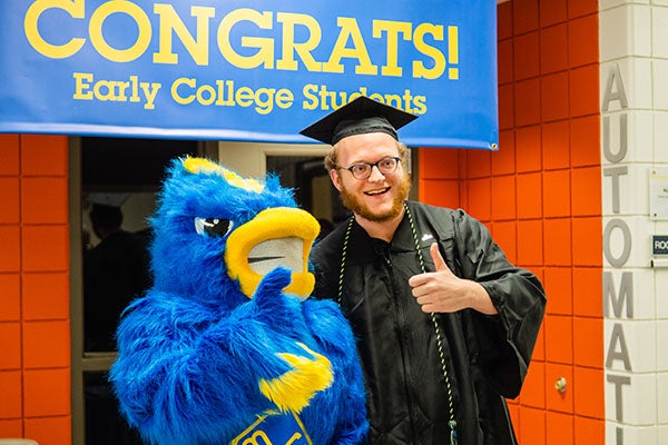 graduating student posing with blue bird mascot