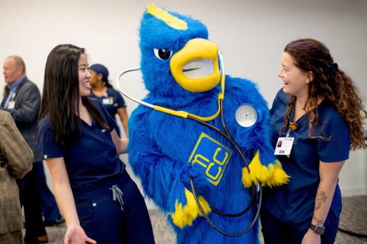 Jay The Jayhawk poses with two nurses while wearing a stethoscope.