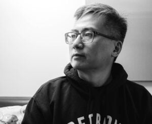 Author Curtis Chin looks to the right and up in a black and white headshot. 