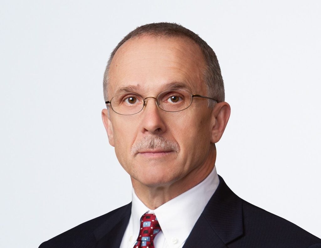 Robert Dubault looks at the camera wearing a tie and glasses