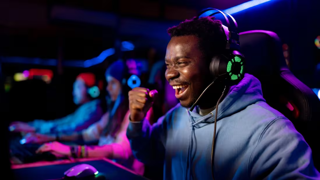 A person playing ESPORTS smiles and pumps his fist in victory.